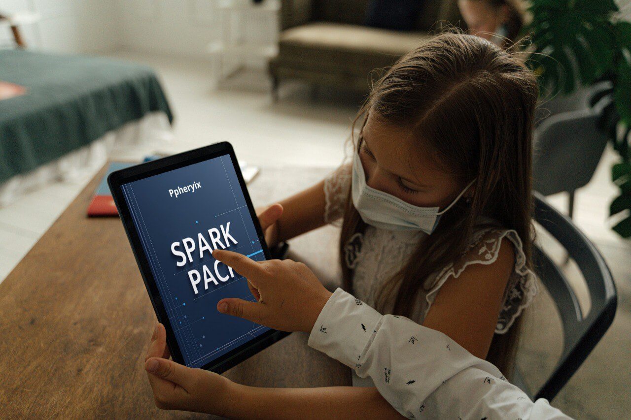 Child using a tablet with 'Pphetyix' and 'Spark Pack' displayed, wearing a mask indoors.